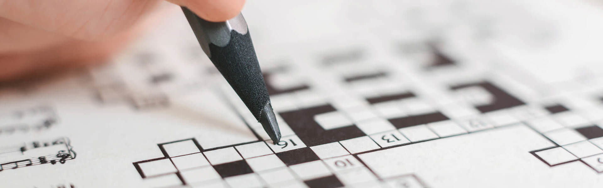 a close up of a person completing a crossword puzzle using a pencil